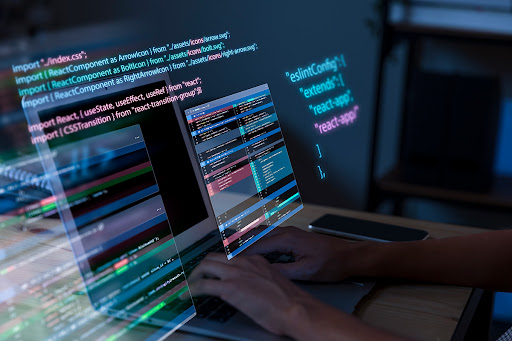 Hands working on a laptop showing codes.